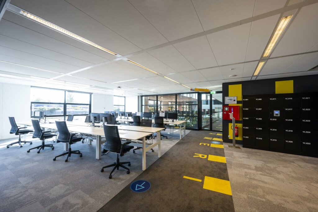 Moderne, open kantoorruimte aan de Piet Heinkade met werkplekken, computerschermen en zwarte lockers.